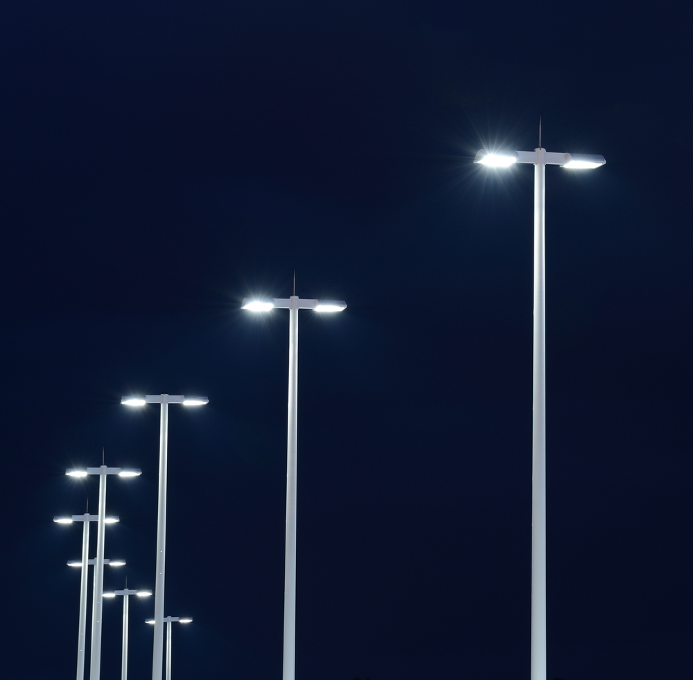 Modern street lights illuminated at night against a dark sky
